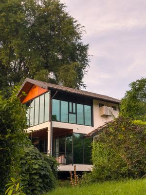Modern two-story villa with floor-to-ceiling windows at The Namkhan eco-resort, surrounded by tropical jungle in Luang Prabang, Laos
