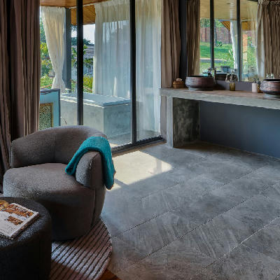 A grey upholstered armchair beside large glass doors in a suite interior.