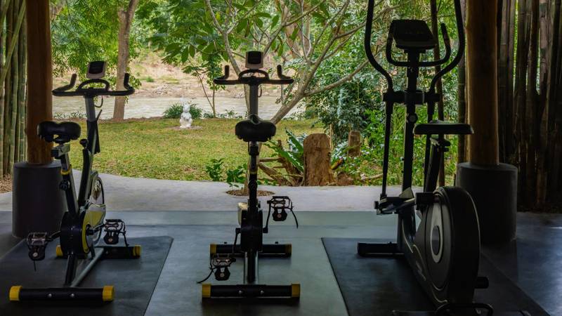 Open-air fitness center with stationary bikes overlooking the Nam Khan River at The Namkhan resort in Luang Prabang, Laos