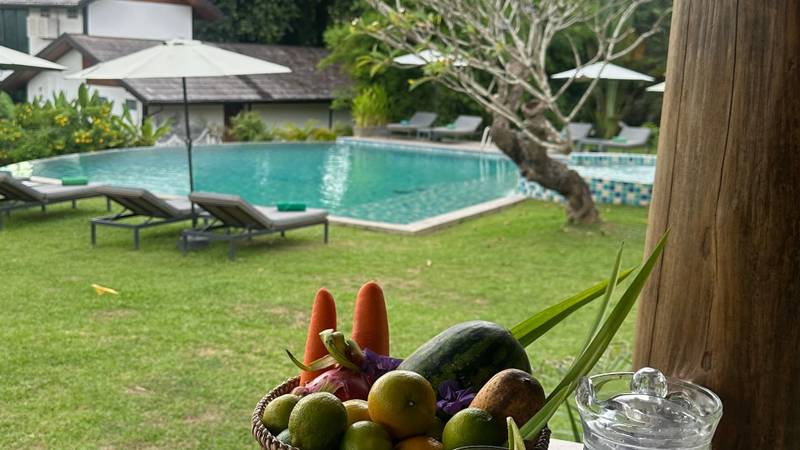 Welcome fruit basket and refreshing drinks at private villa terrace overlooking pool at The Namkhan resort in Luang Prabang, Laos