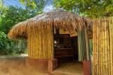 Open-air bamboo bathroom with thatched roof at The Namkhan villa in Luang Prabang, featuring natural materials and tropical garden views