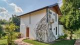 Two-storey white villa with large banyan tree mural on exterior wall surrounded by greenery.
