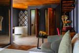 View into ensuite bathroom with freestanding tub and ornate wall art at The Namkhan resort suite in Luang Prabang, featuring warm wood tones and contemporary...