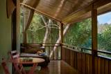 Private wooden terrace at The Namkhan treehouse villa in Luang Prabang, featuring forest views, daybed, and natural light through the canopy.