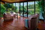 Spacious suite lounge with floor-to-ceiling windows overlooking lush jungle at The Namkhan eco-resort in Luang Prabang, Laos