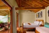 Warm timber guest room with terrace at The Namkhan boutique hotel in Luang Prabang, featuring handwoven textiles and open-air design