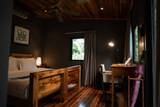 Guest room interior at The Namkhan in Luang Prabang featuring dark walls, teak wood flooring, comfortable bed, and workspace desk