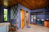The Namkhan villa suite bathroom entrance in Luang Prabang featuring decorative wallpaper, warm wooden ceiling, freestanding tub, and tropical garden views