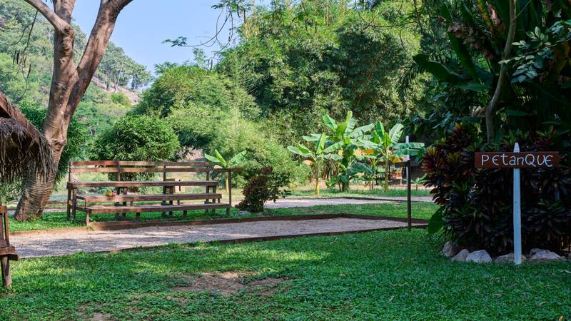 Petanque court with wooden benches surrounded by tropical gardens near The Namkhan resort in Luang Prabang, Laos