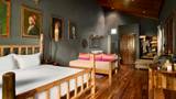 Art Deluxe Suite bedroom with dark grey walls, teak floors, bamboo bed frame, and pink silk daybed cushions.