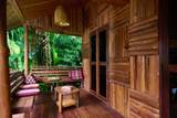 Wooden terrace with traditional Lao cushions and bamboo seating overlooking tropical gardens at The Namkhan, Luang Prabang, Laos