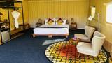 A glamping tent bedroom with a white-dressed double bed, colourful patterned rug, and warm yellow canvas walls.