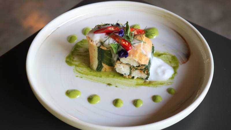 Elegantly plated seafood dish with shrimp, herb garnish, and green sauce dots on white ceramic plate at Namkhan restaurant