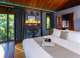Spacious king bedroom at The Namkhan resort in Luang Prabang, featuring wooden floors, contemporary Lao artwork, and tropical garden views