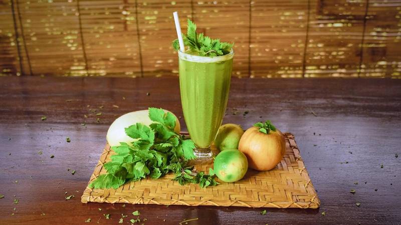 Fresh green juice with local herbs and fruits on woven bamboo tray at The Namkhan restaurant in Luang Prabang, Laos