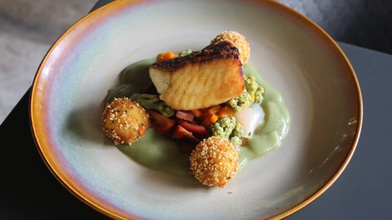 Artfully plated seared fish with sesame-crusted croquettes, seasonal vegetables, and herb puree served on ceramic dinnerware at Namkhan restaurant
