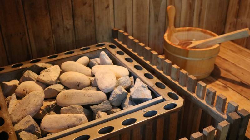 Private sauna with hot stones and wooden bucket at The Namkhan wellness facilities in Luang Prabang, Laos, offering traditional heat therapy.