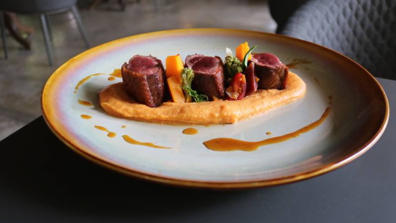 Three seared beef medallions with vibrant vegetables on a golden-rimmed plate, showcasing fine dining at Namkhan's riverside restaurant