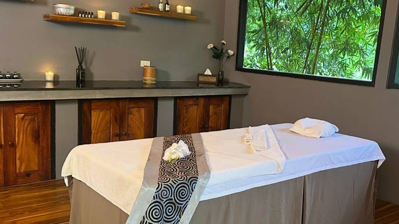 Serene spa treatment room at The Namkhan in Luang Prabang featuring massage tables, natural wood cabinetry, and bamboo forest views