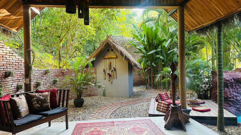 Open-air spa relaxation pavilion with traditional seating and tropical gardens at The Namkhan resort in Luang Prabang, Laos