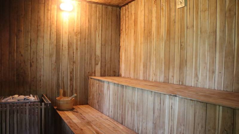 Traditional wooden sauna interior with tiered benches and bucket at The Namkhan wellness facility in Luang Prabang, Laos