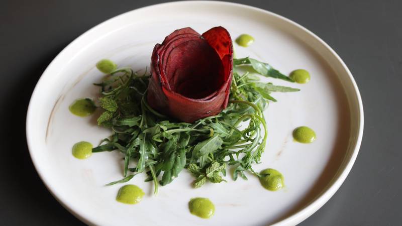 Artfully plated beetroot rose with fresh arugula and herb-infused dressing on white porcelain, showcasing fine dining at Namkhan resort