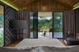 Spacious villa bedroom at The Namkhan with floor-to-ceiling glass doors opening to private terrace overlooking tropical gardens in Luang Prabang