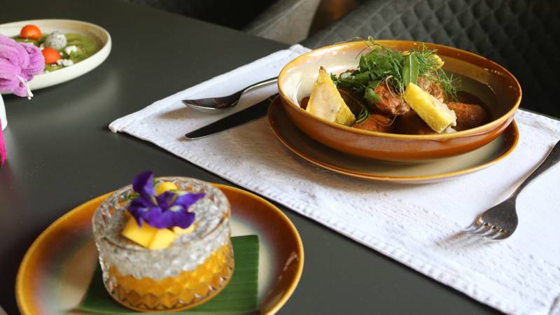Traditional Lao lunch dishes served on handcrafted ceramic plates with fresh herbs, grilled fish, and mango sticky rice dessert — The Namkhan Luang Prabang