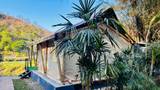 Canvas safari tent with wooden deck overlooking the Nam Khan River at The Namkhan eco-resort in Luang Prabang, Laos, framed by tropical palms