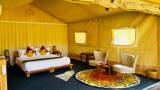Interior of a luxury tent at The Namkhan in Luang Prabang, featuring yellow quilted walls, cream armchairs, and handwoven textiles.