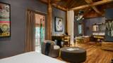 Spacious hotel suite with teak beams, original artwork, armchair, and balcony view.