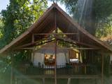 Open-air elevated deck sala at The Namkhan riverside villa in Luang Prabang, featuring traditional teak timber architecture and daybed seating