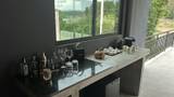 Dark granite bar counter with glassware, spirits, and coffee machine framing a jungle river view.