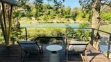 Rattan chairs and a small table on a wooden deck overlooking the green Namkhan River.