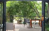 Private wooden deck with dining table and chairs overlooking tropical forest at The Namkhan villa in Luang Prabang, Laos