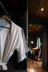 Plush waffle-weave bathrobe hanging in a modern bathroom at The Namkhan resort in Luang Prabang, featuring dark walls and warm lighting