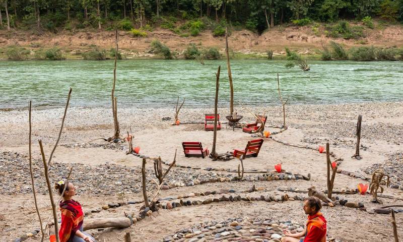 Guests meditating in a riverside stone circle at The Namkhan wellness retreat overlooking the Nam Khan River in Luang Prabang, Laos