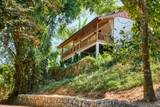 Traditional wooden hillside villa at The Namkhan resort in Luang Prabang, nestled among lush tropical forest with elevated terrace balcony.