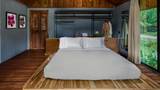 A neatly made white bed in a teak-panelled suite with open wardrobe behind.