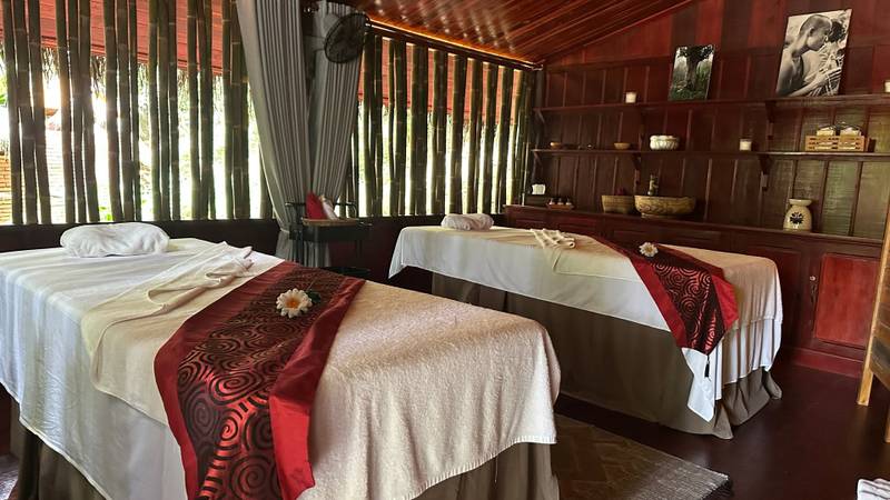Serene spa treatment room with twin massage beds at The Namkhan resort in Luang Prabang, featuring rich teak wood interiors and natural light