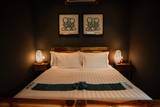 Cozy guest room at The Namkhan in Luang Prabang featuring wooden furniture, warm bedside lamps, local artwork, and crisp white linens.