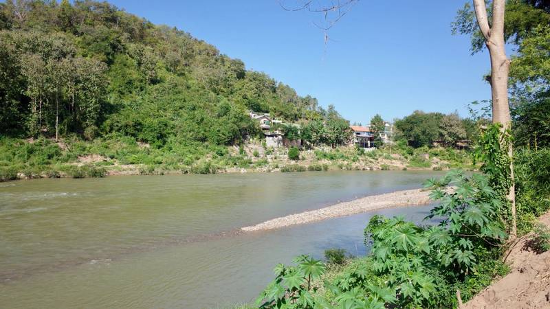 The Namkhan resort nestled along the riverbank surrounded by lush tropical hills and the Nam Khan River in Luang Prabang, Laos