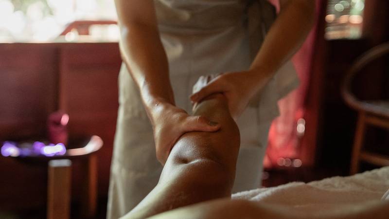 Therapist performing traditional massage treatment at The Namkhan spa in Luang Prabang, with natural light and river views
