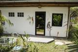Private villa terrace at The Namkhan resort in Luang Prabang featuring black-framed glass doors, white walls, tropical palms, and garden seating
