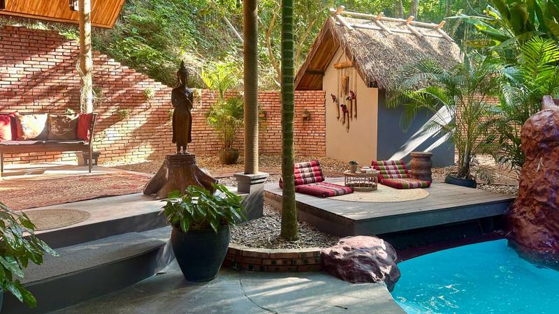 The Namkhan resort pool meditation deck with traditional Lao pavilion, Buddha statue, and colorful cushions in Luang Prabang, Laos