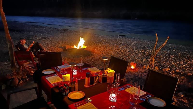 Private beachside dinner setup with fire pit at The Namkhan resort overlooking the river in Luang Prabang, Laos at twilight