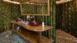 A bamboo-walled bathroom with a red stone vessel sink on a teak wood vanity.